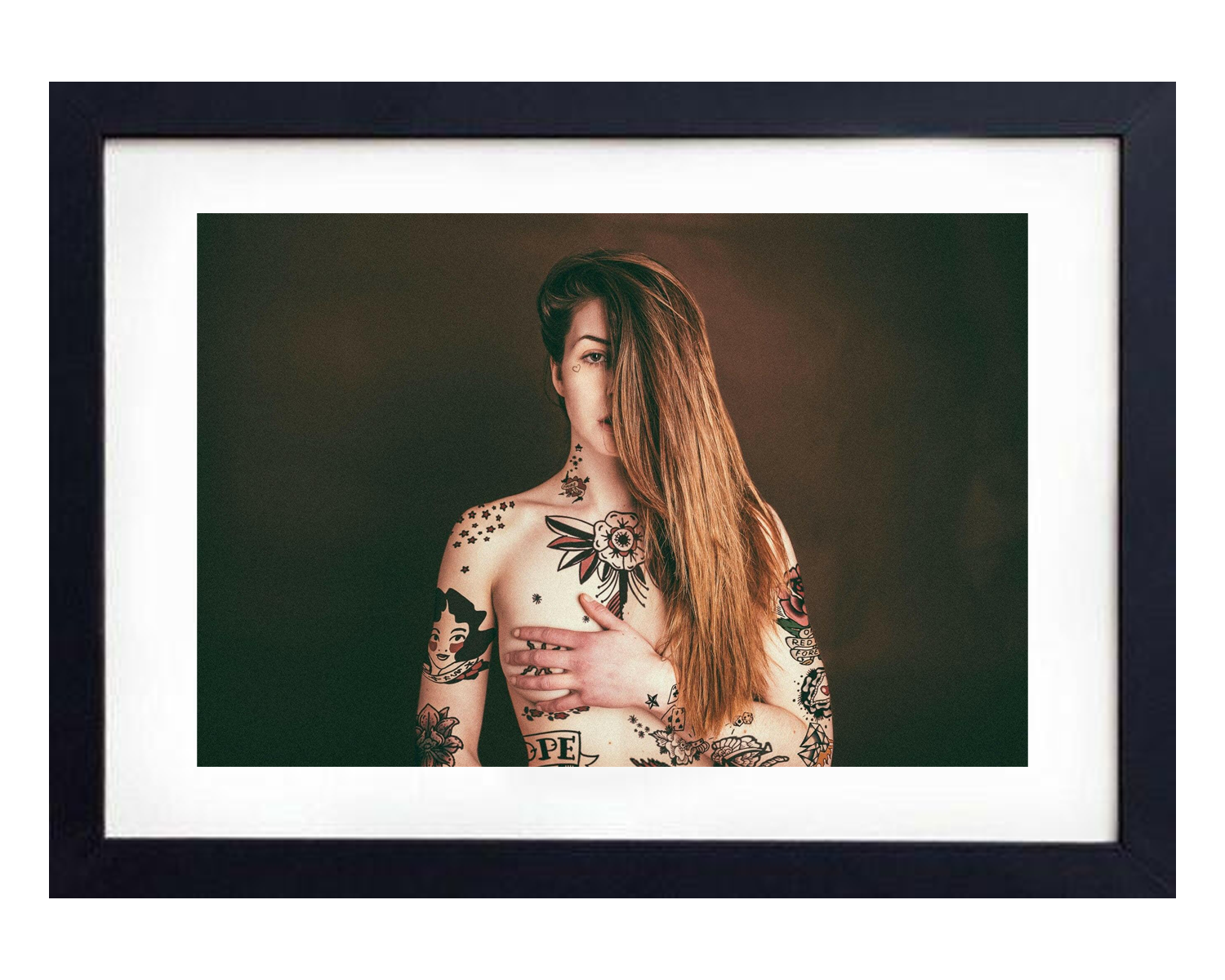Framed portrait of a woman with tattoos on a dark background