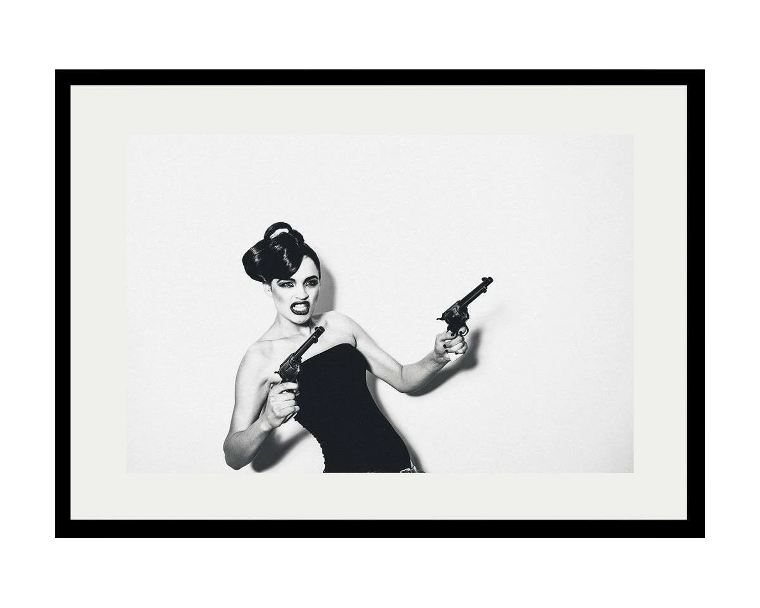 Framed black and white artwork of a woman holding two revolvers.