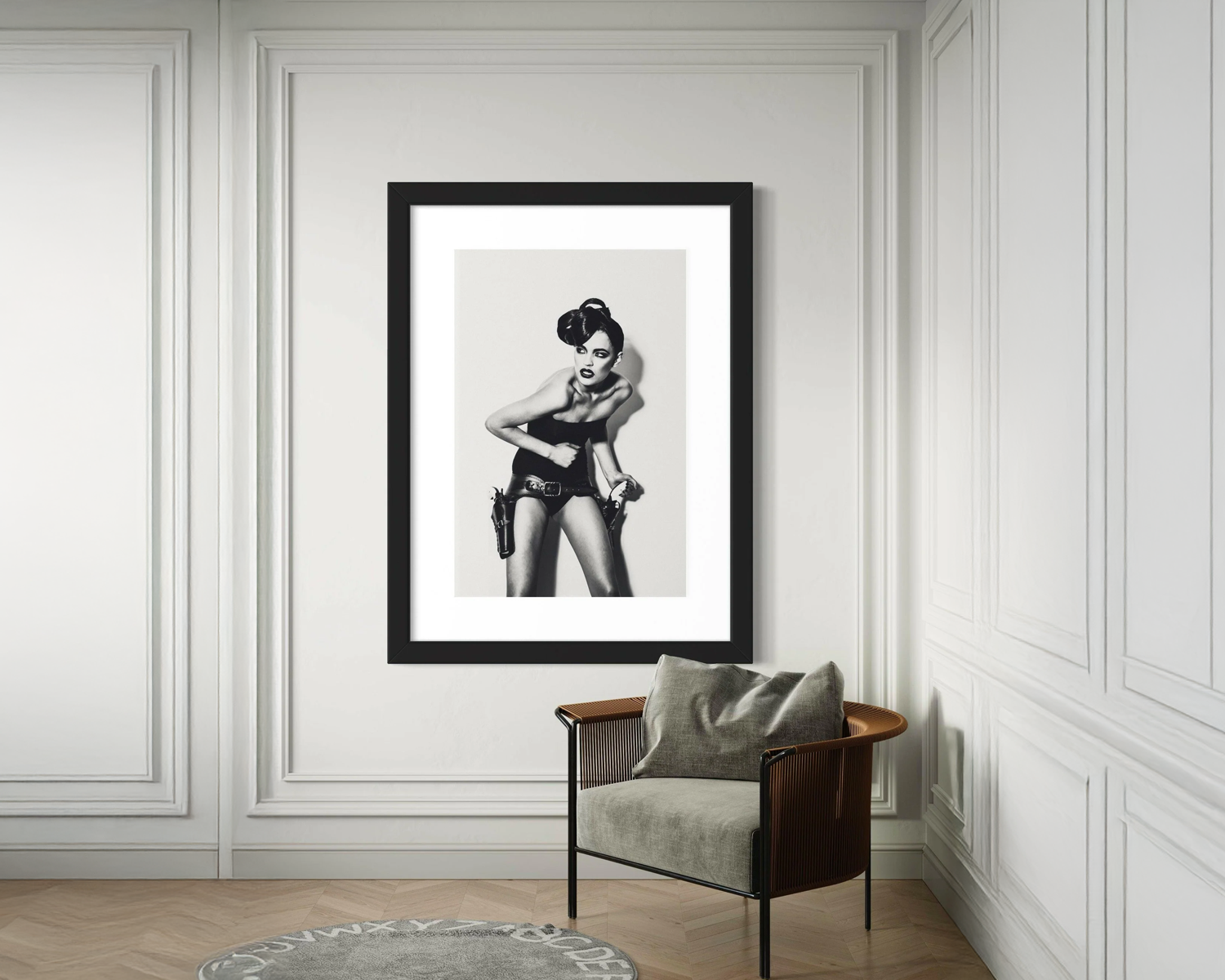 Framed black and white artwork of a woman in a stylish pose on a wall with a chair below.