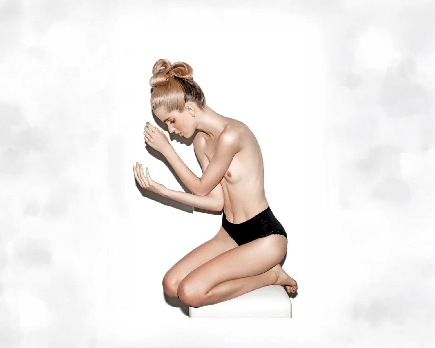 Woman in black underwear kneeling on a white background