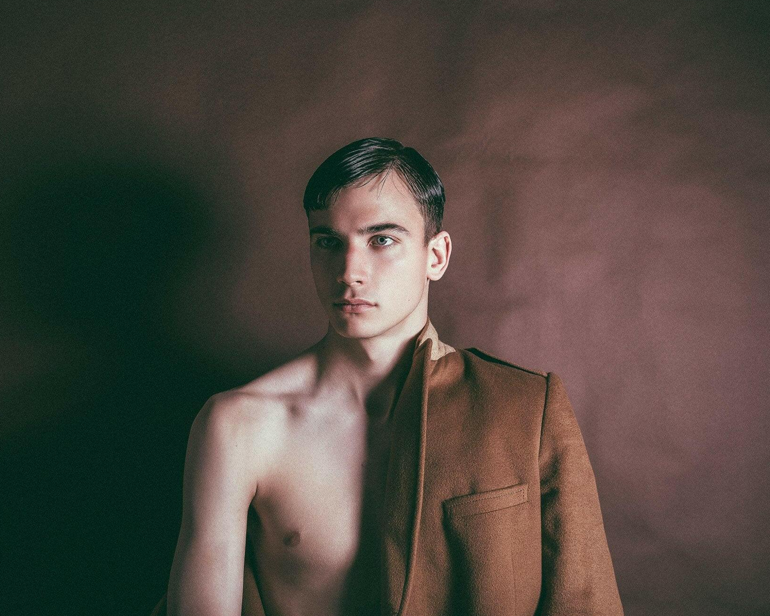 Man wearing a brown jacket against a dark background