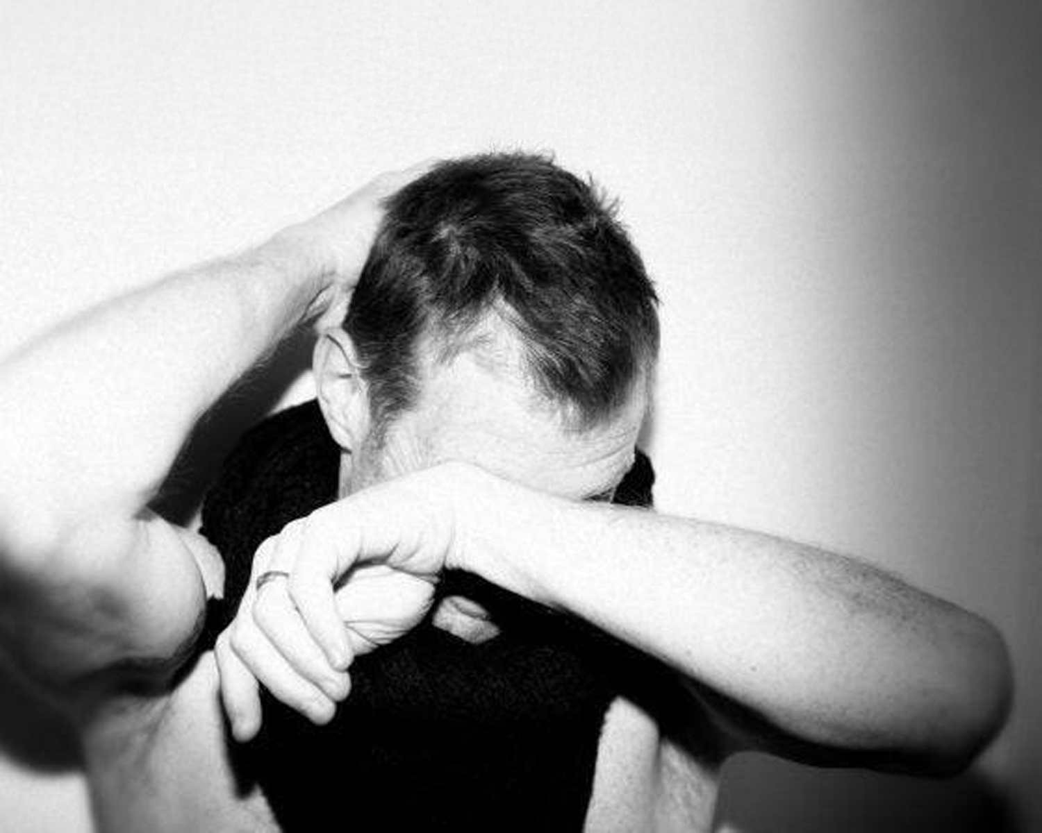 Person with head in hands against a plain background