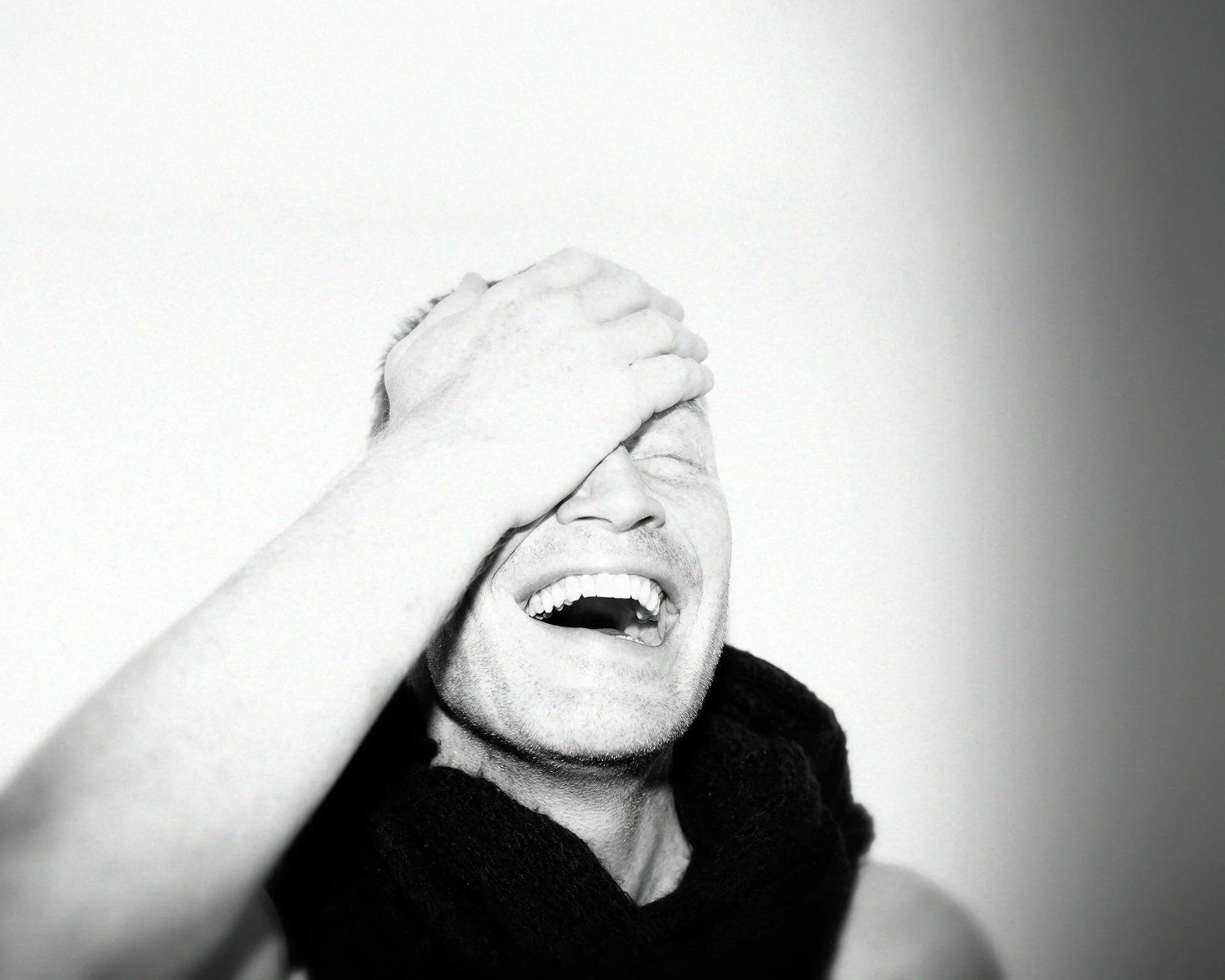 Person with hands over face against a white background