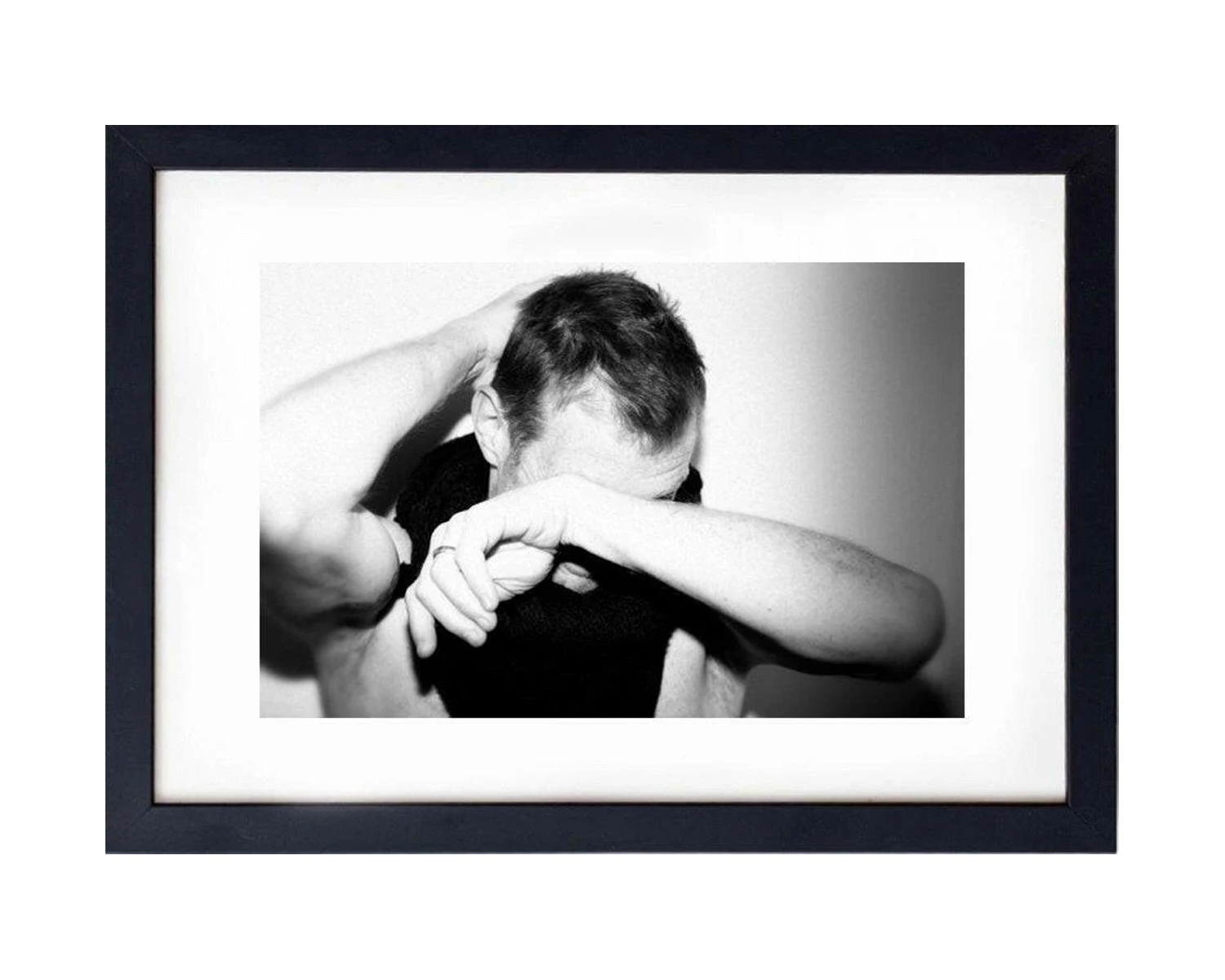 Framed black and white photo of a person with their head in their hands.