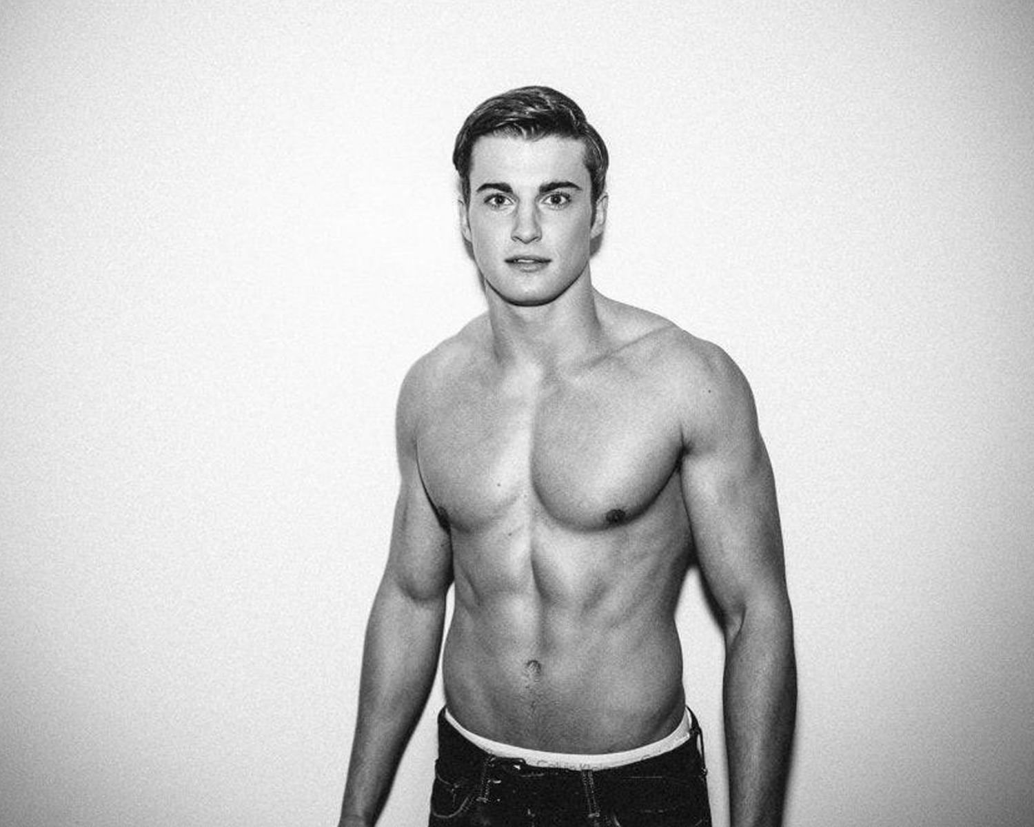 Black and white photo of a shirtless man against a plain background