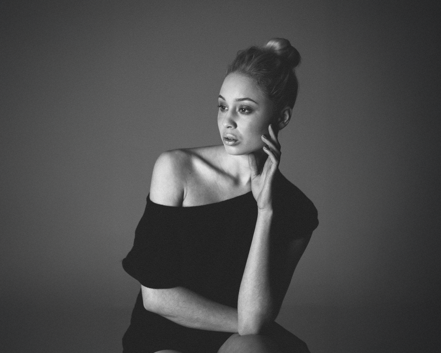 Black and white portrait of a woman posing against a plain background