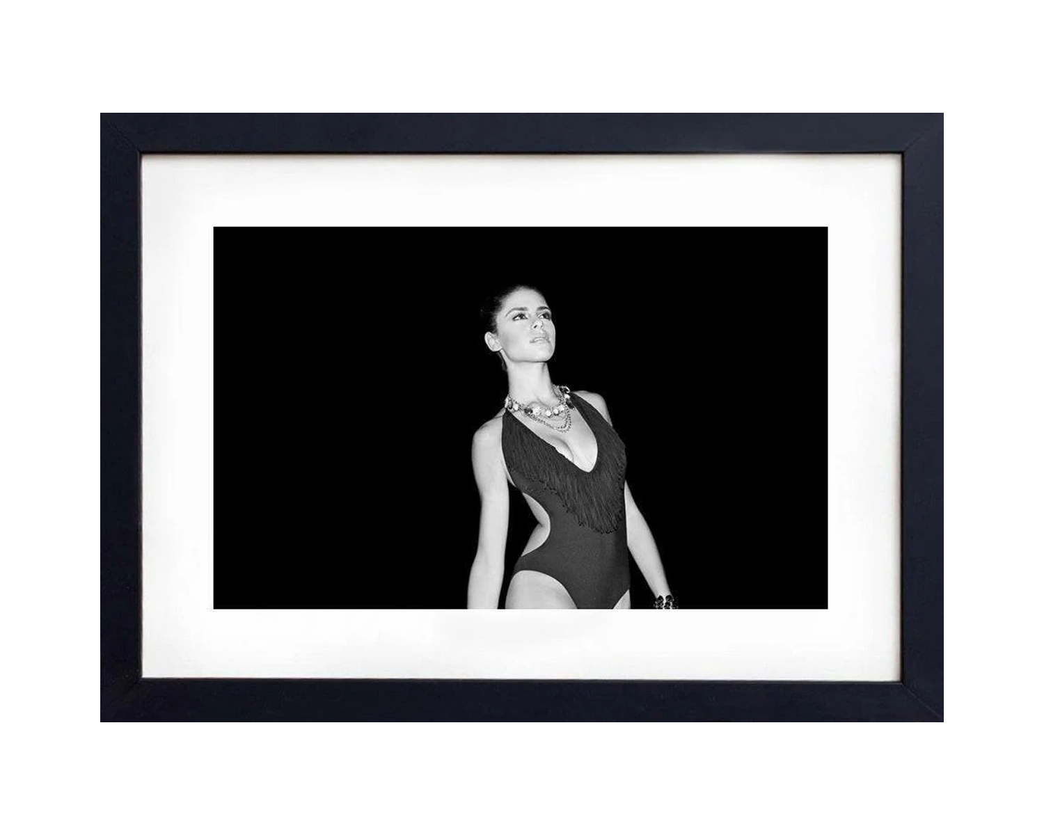 Framed black and white portrait of a woman in a swimsuit against a black background.