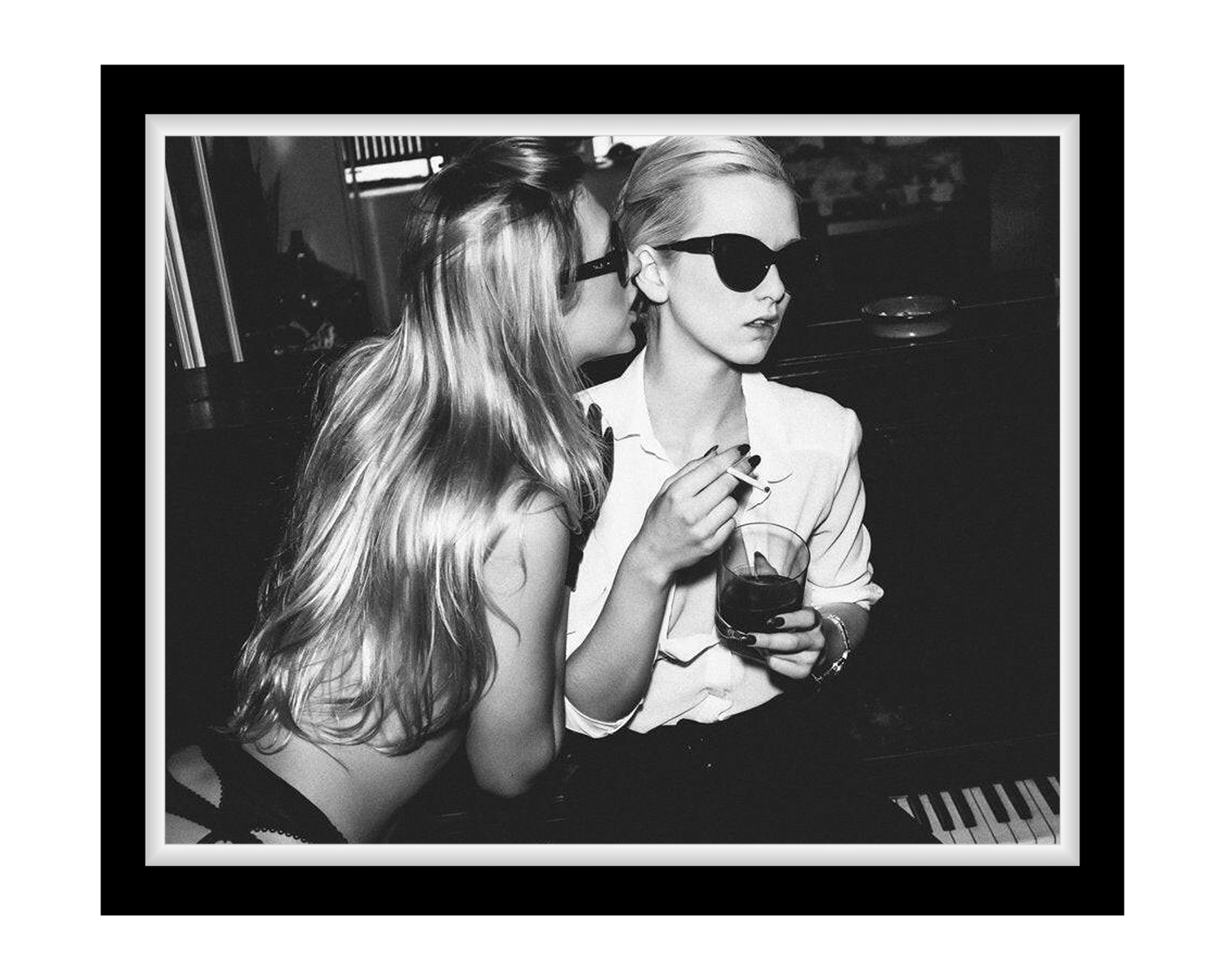 Two women in a nightclub setting, one whispering to the other and holding a drink.