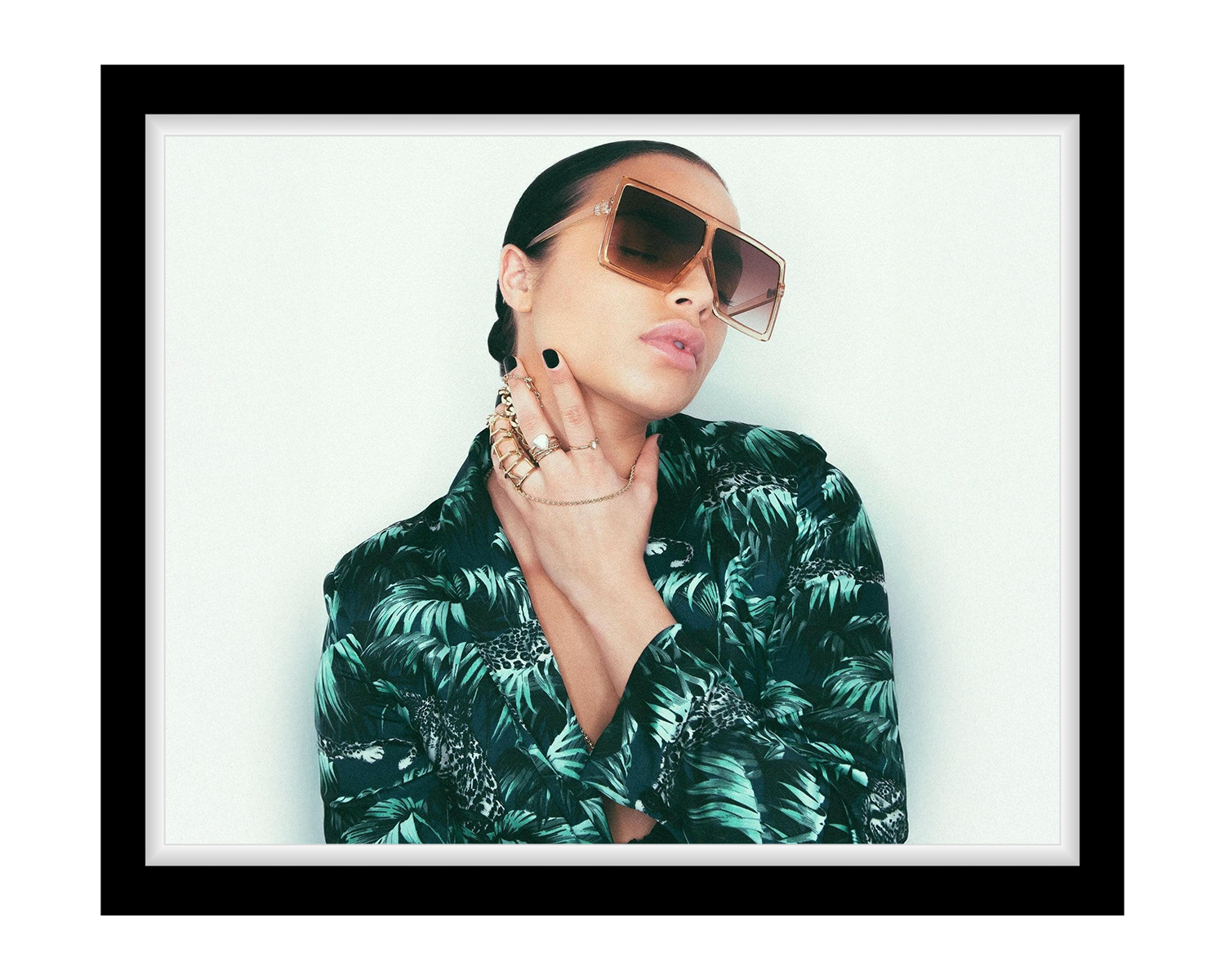 Woman wearing sunglasses and a patterned shirt with a white background