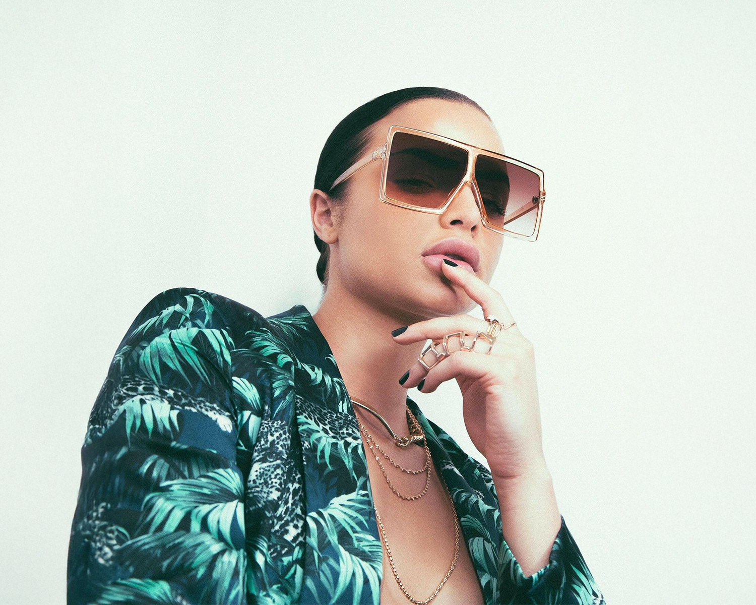 Woman wearing sunglasses and a patterned top with a neutral background