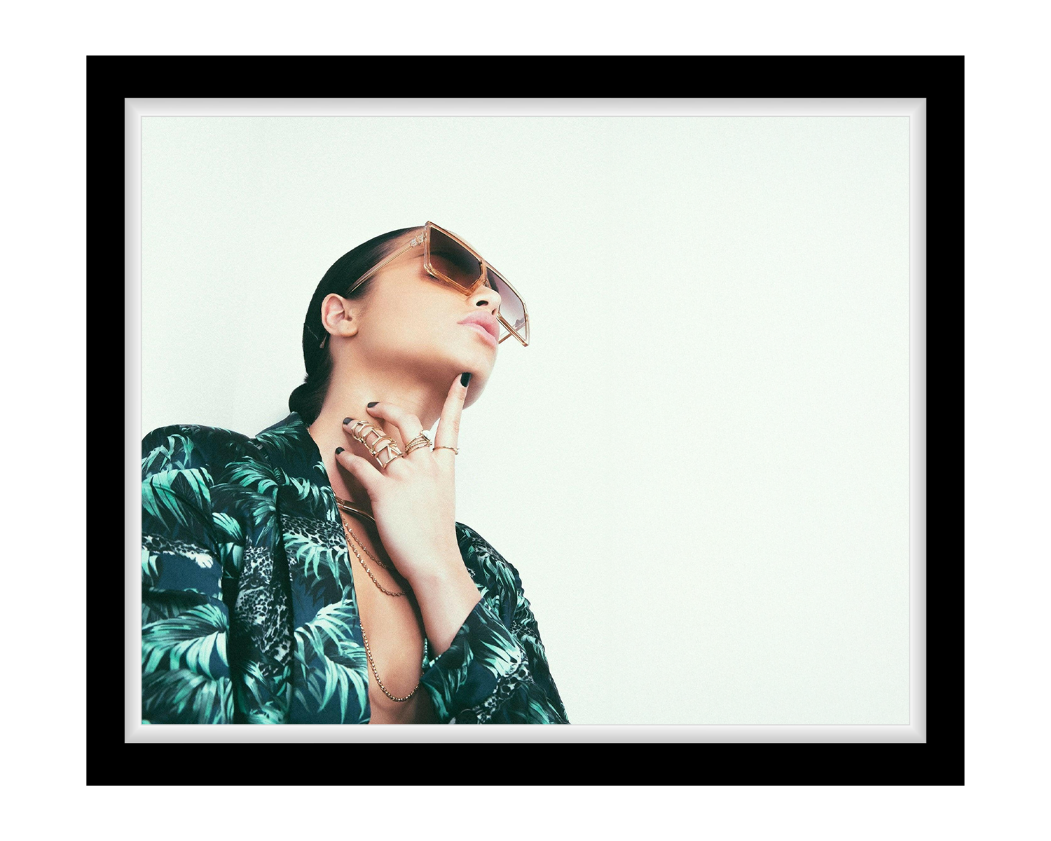 Lady wearing sunglasses and a patterned shirt with a white background