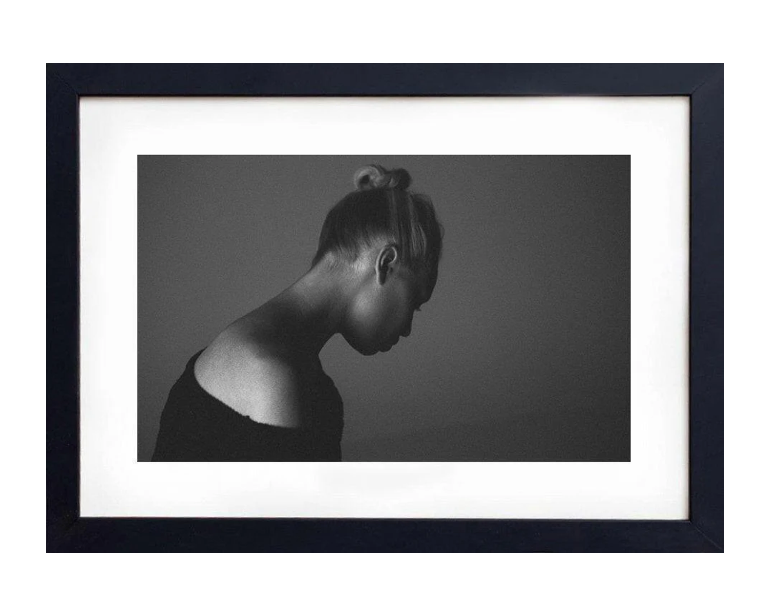 Framed black and white portrait of a woman with her head bowed against a dark background