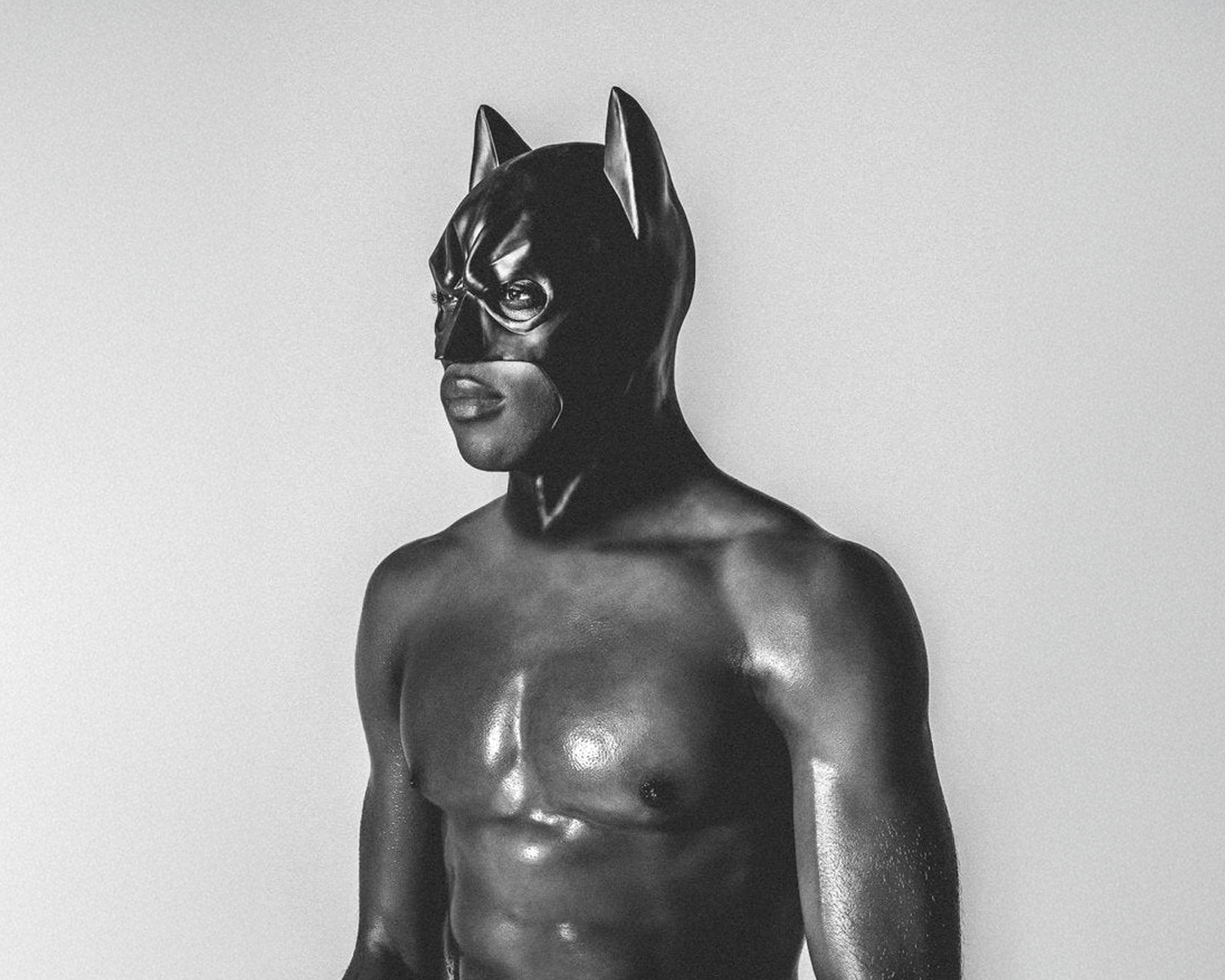 Person wearing a black cat mask against a plain background