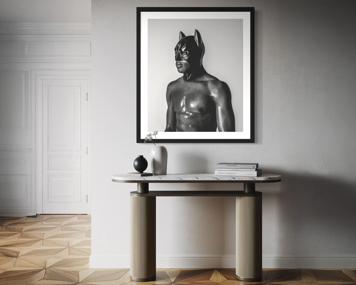 Framed black and white artwork of a masked figure on a wall above a console table.
