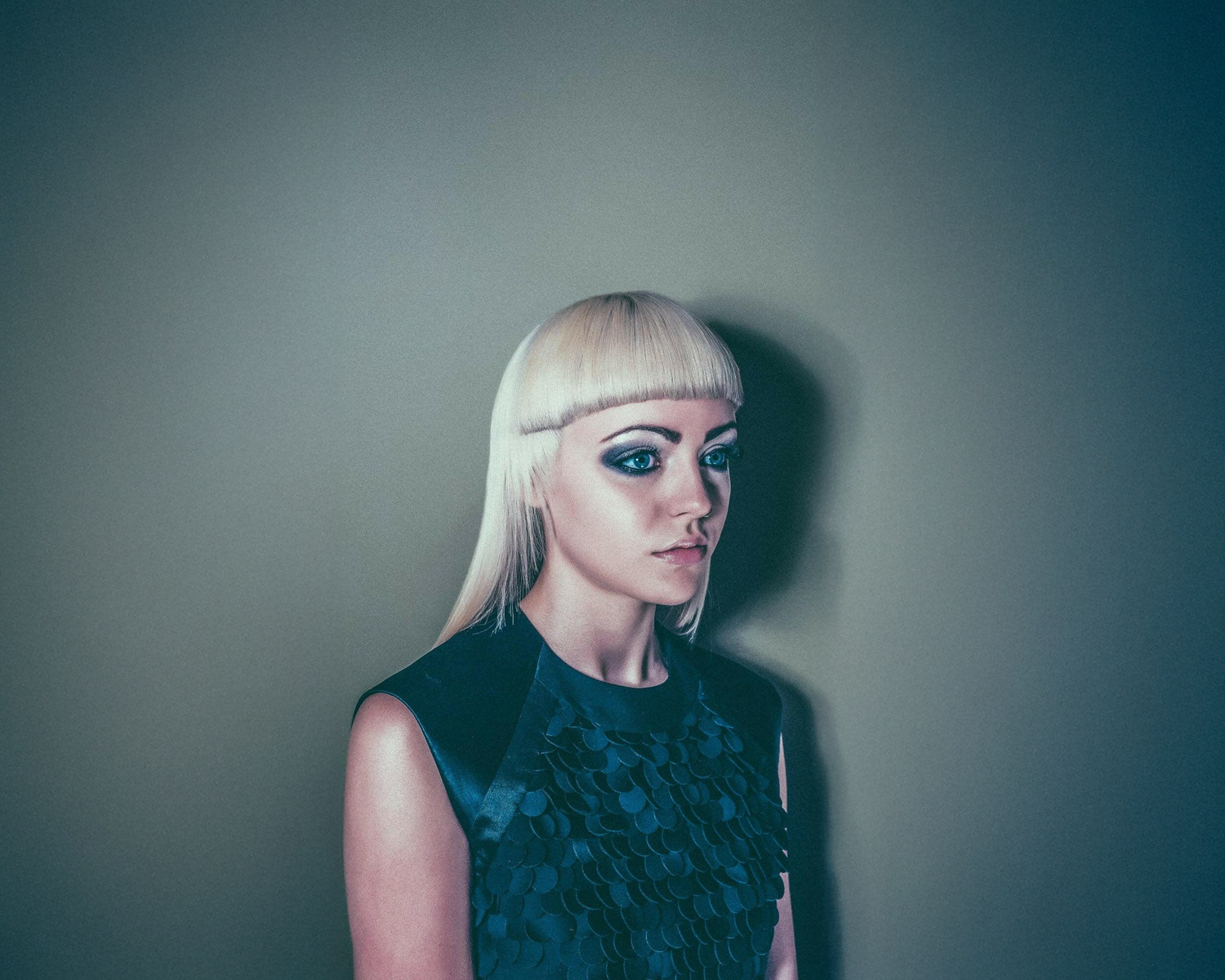 Girl with a blonde bob haircut against a plain background