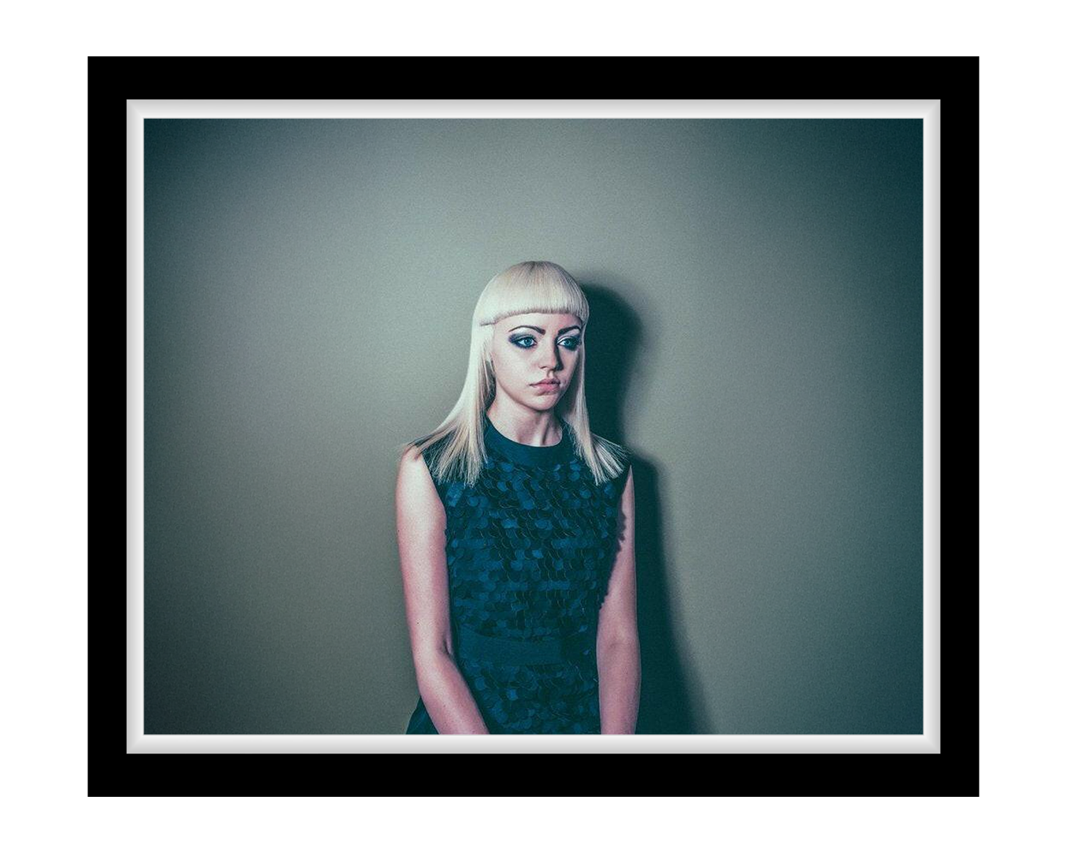 Lady with blonde hair and dark makeup against a plain background