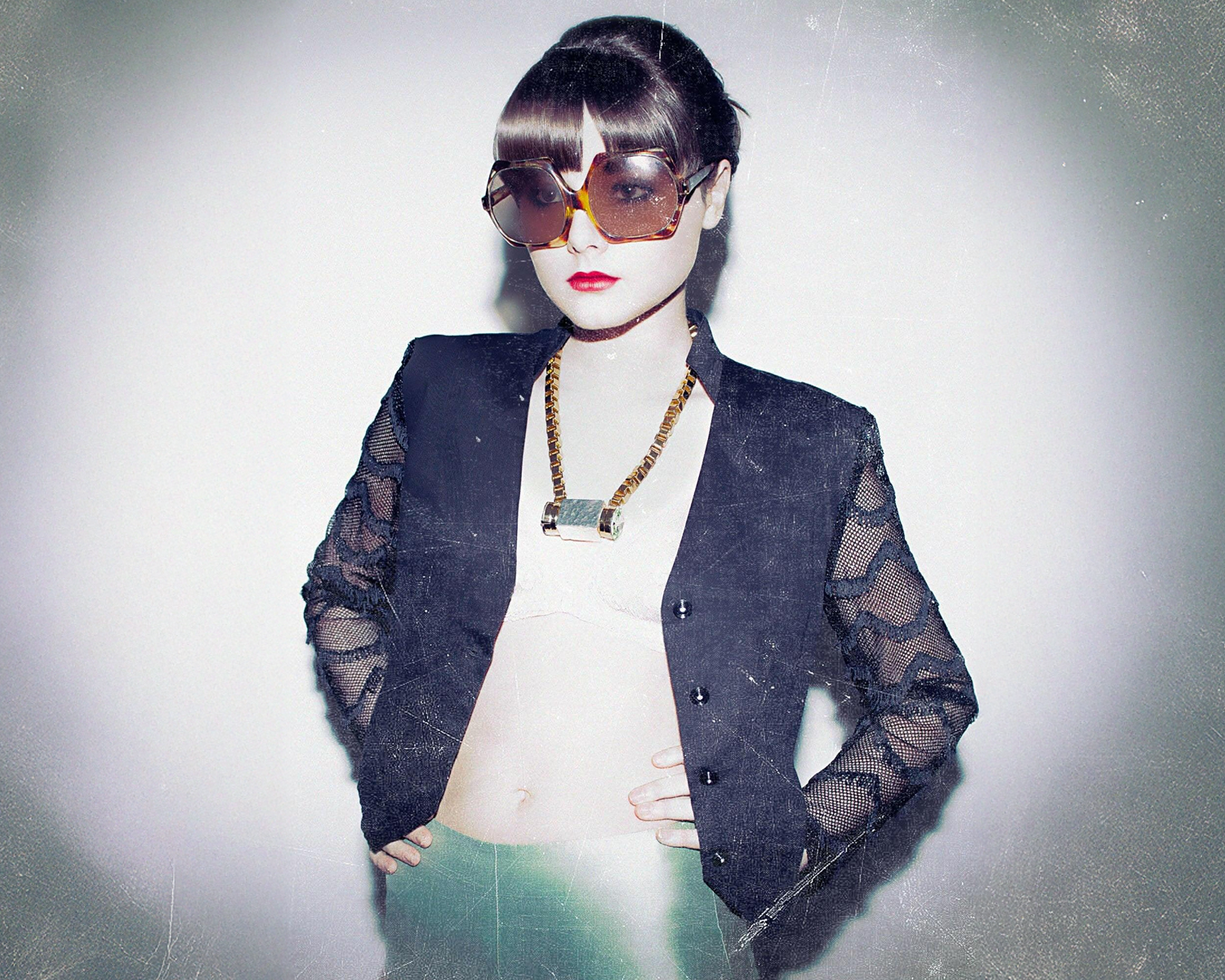 Girl wearing a dark blue sheer jacket over a white top with sunglasses and a necklace.
