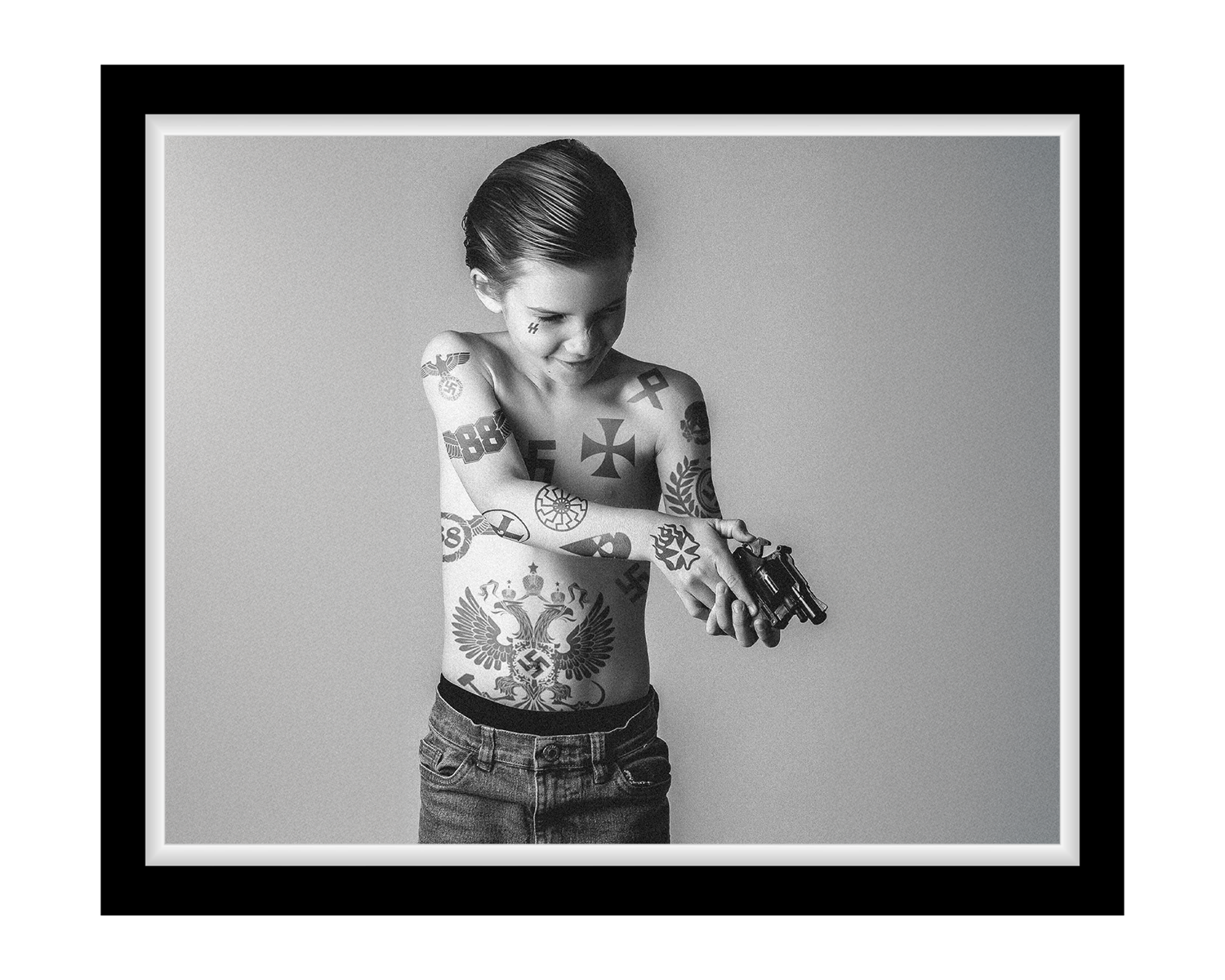 Black and white photo of a person with tattoos on a plain background