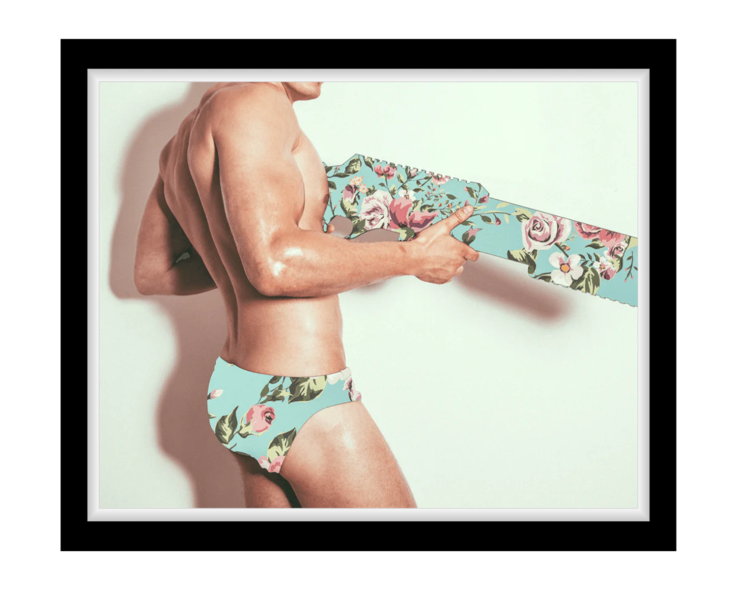 Man wearing floral underwear holding a floral-patterned gun against a light background