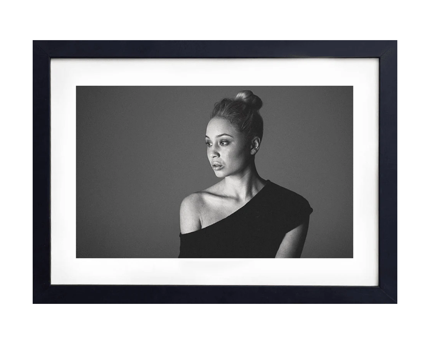 Framed black and white portrait of a woman with a bun against a gray background