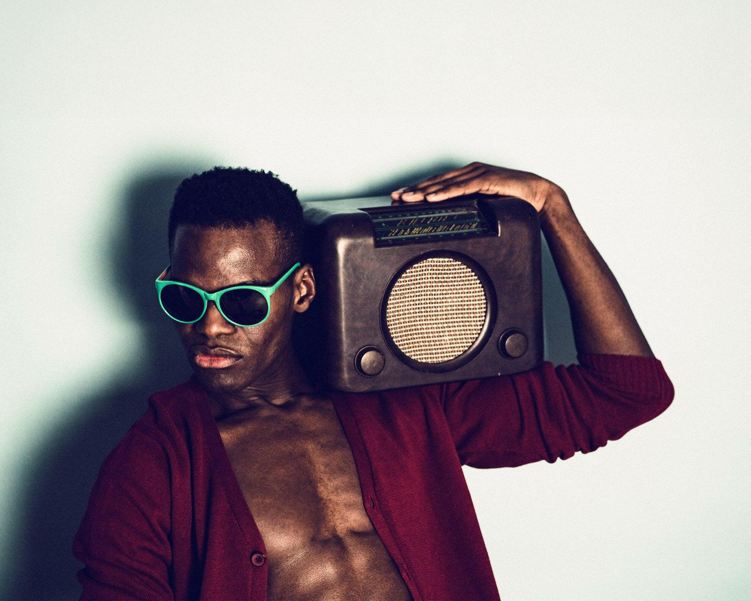 Man holding a vintage radio against his head with a minimal background