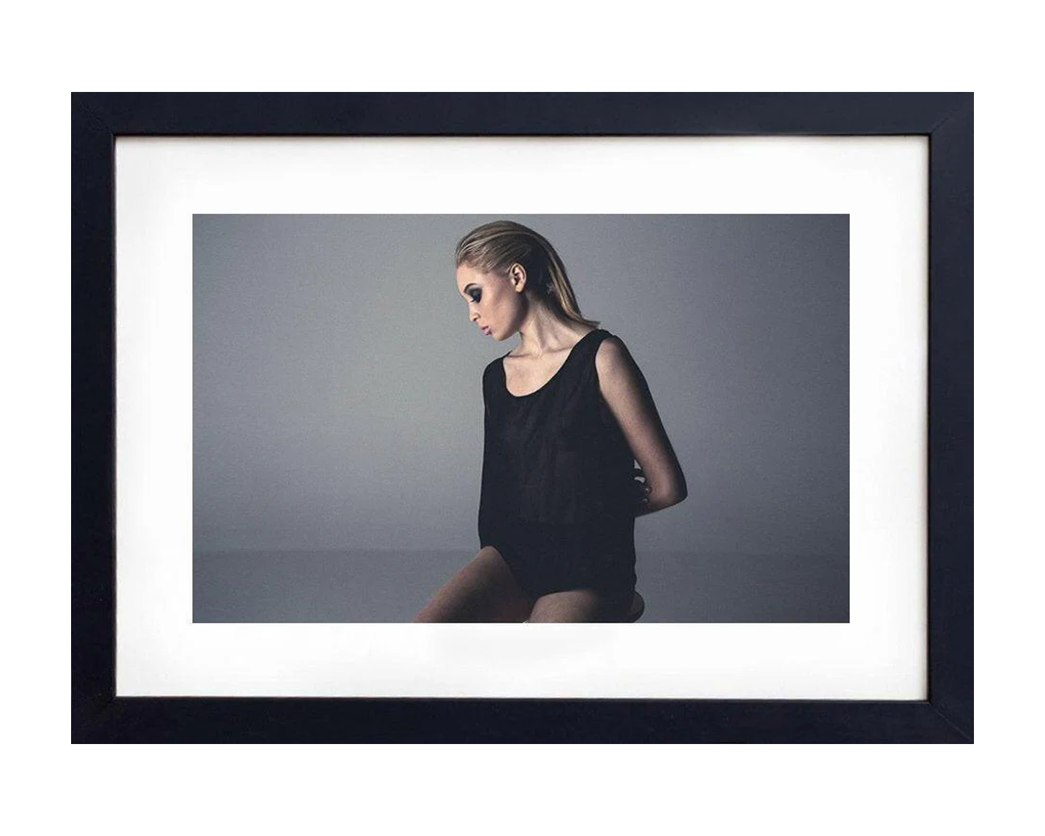 Framed photograph of a person wearing a black outfit against a gray background