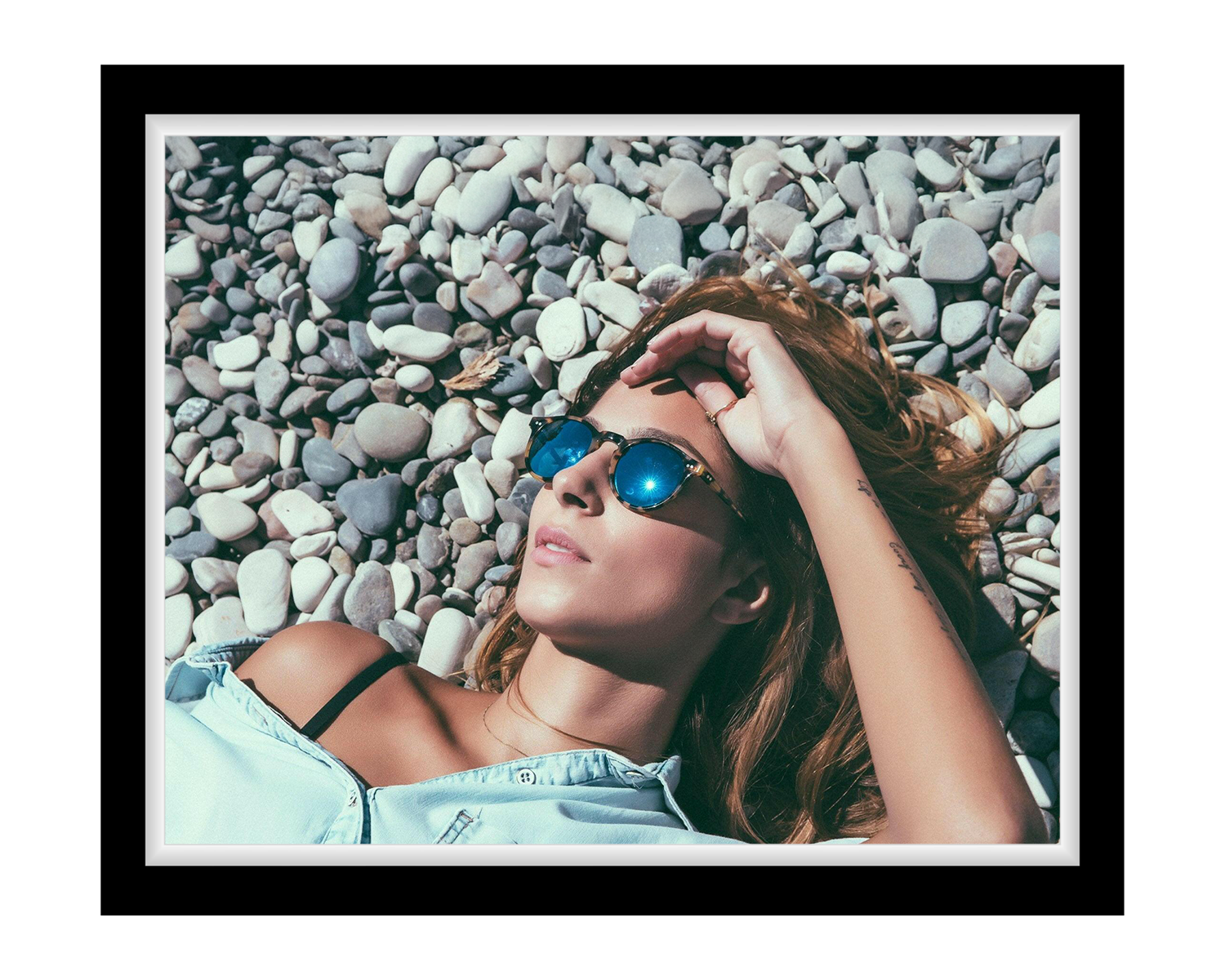 Woman wearing sunglasses lying on pebbles