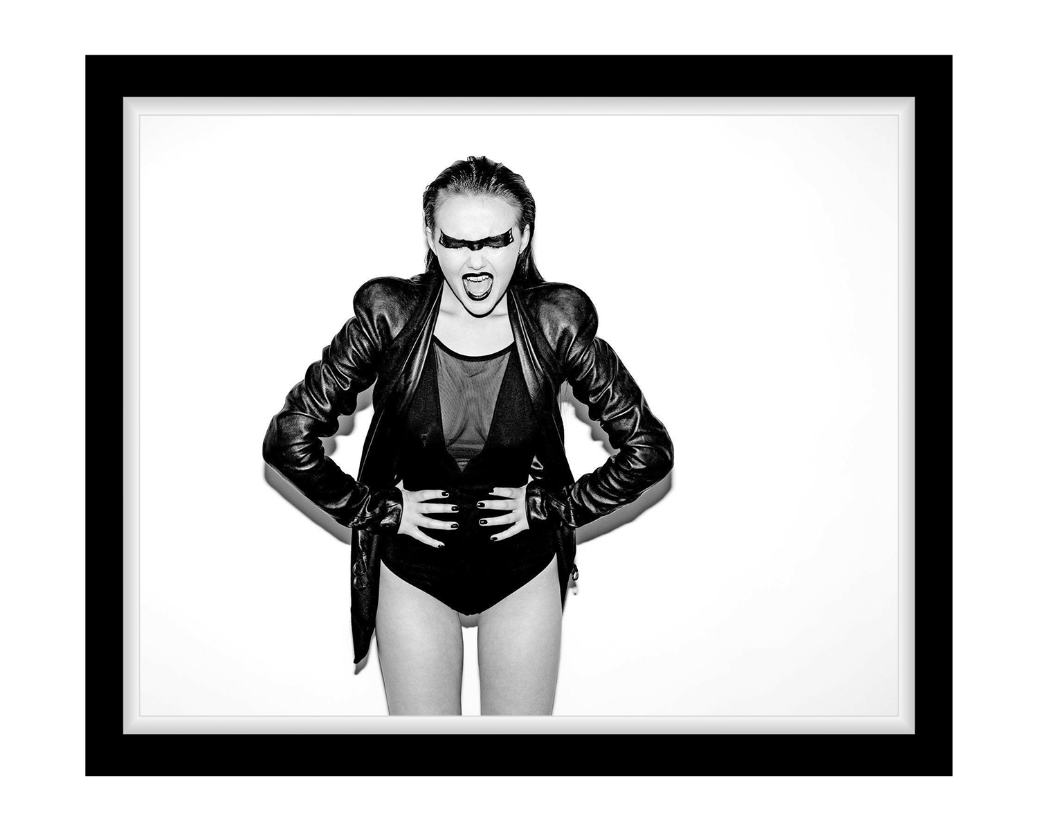 A woman in a black leather jacket paired with underwear, showcasing a bold fashion statement in a studio setting.
