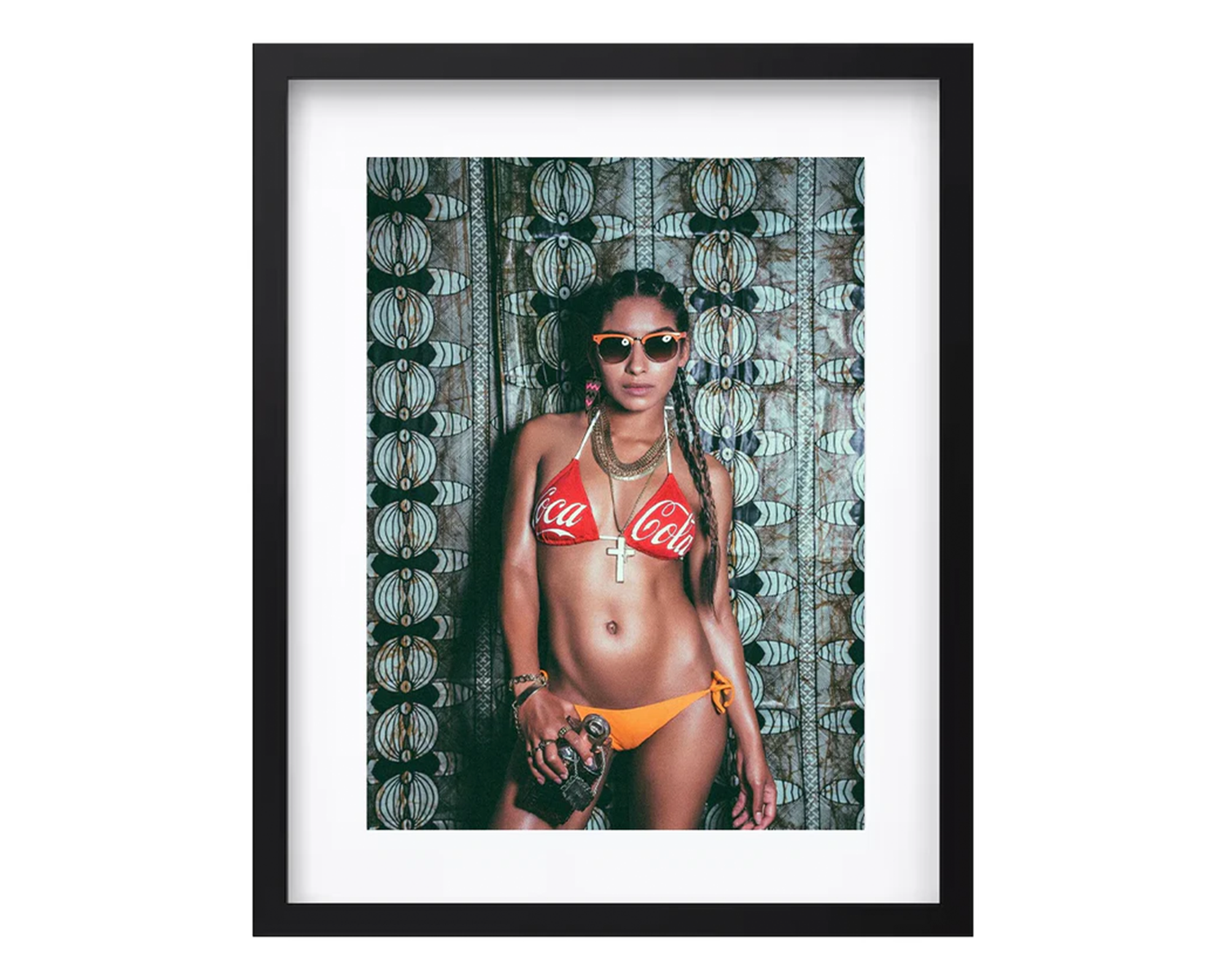 A woman in a bikini and sunglasses poses confidently in front of a colorful wall, framed in black.
