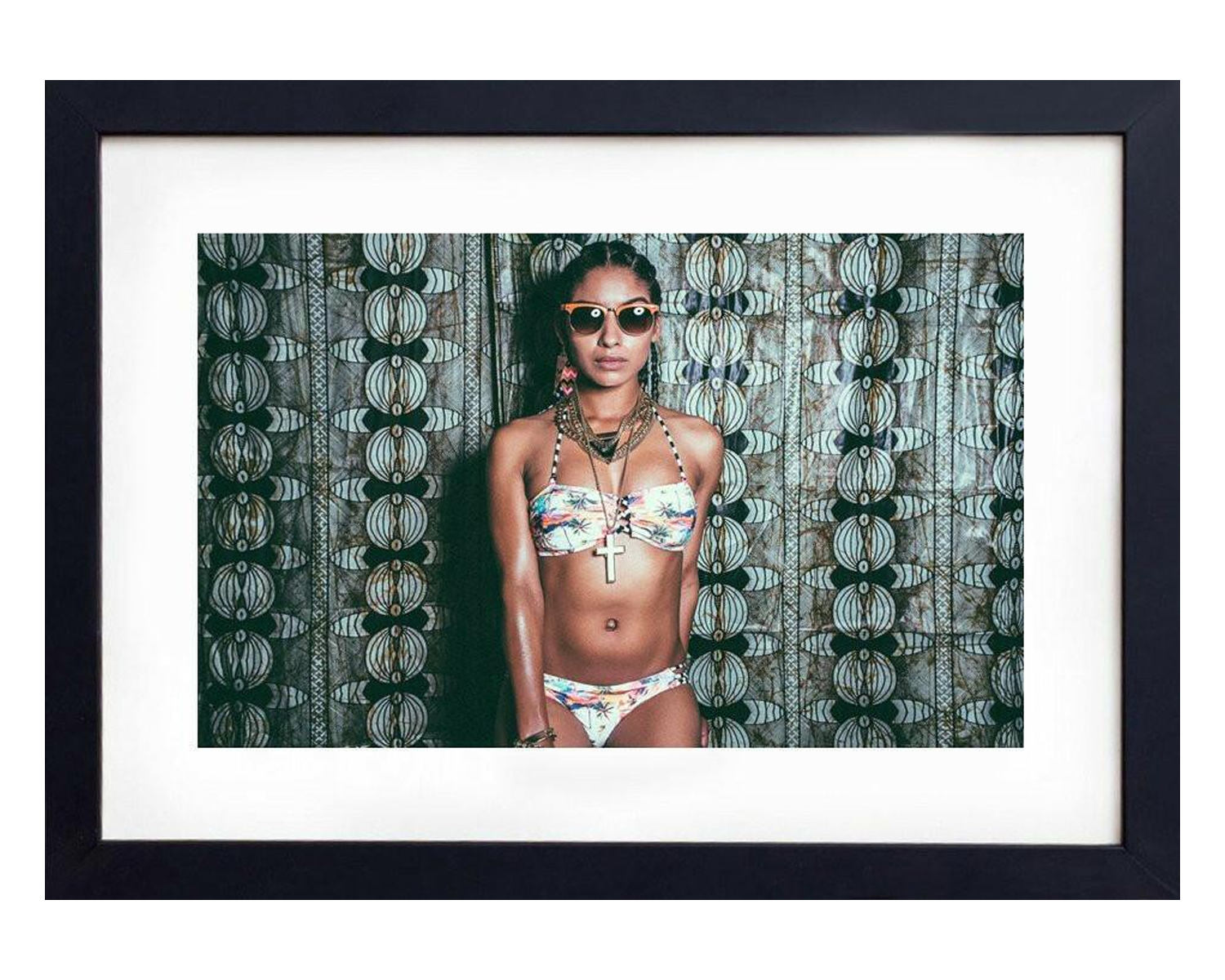 A woman wearing a bikini and sunglasses strikes a pose for a photo, exuding confidence and enjoying a sunny day, framed in black.